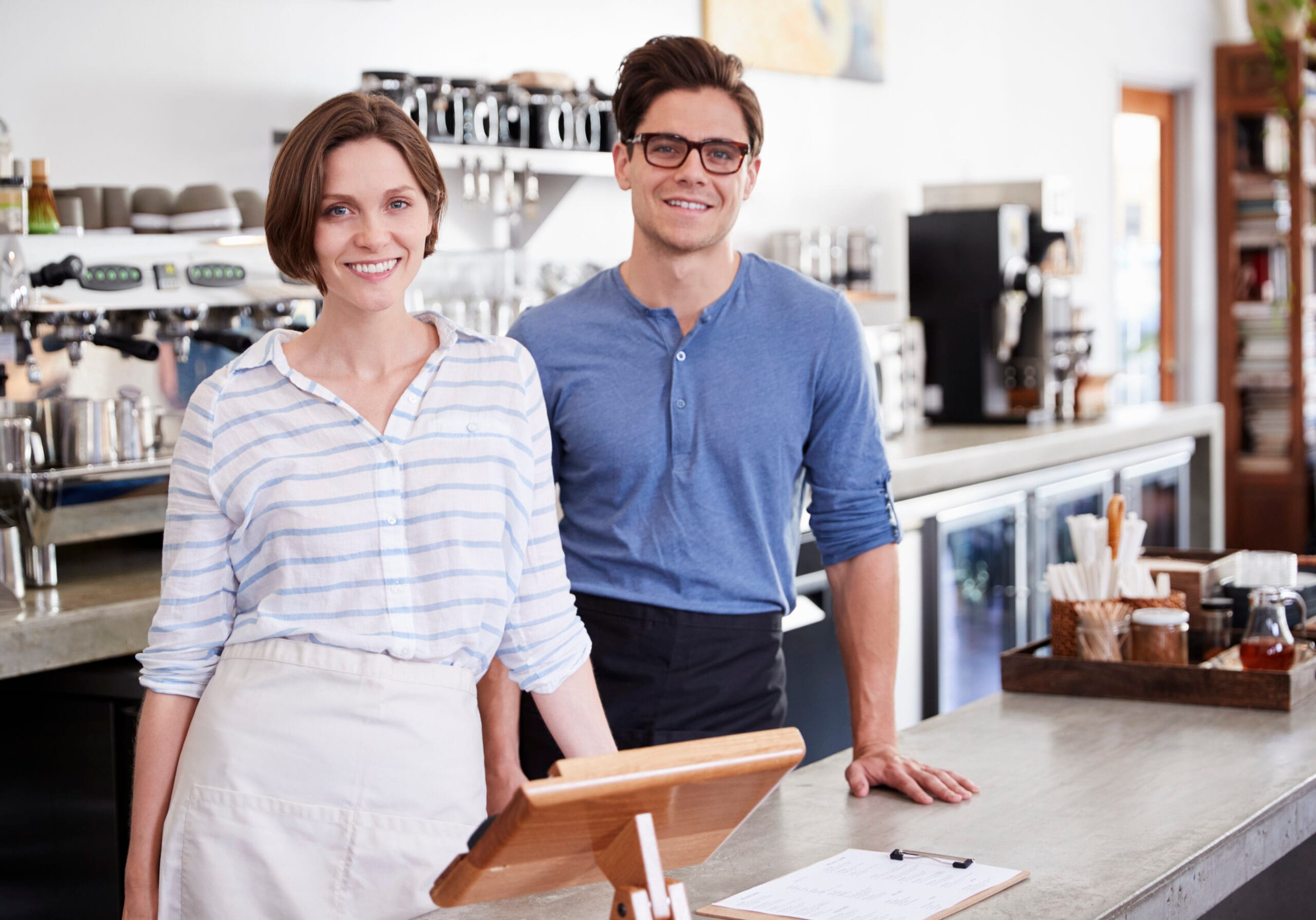 smiling woman wearing glasses placing freshly baked pastry