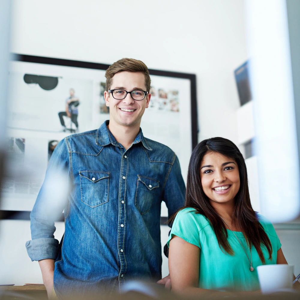 Two business people standing next to each other smiling at the camera